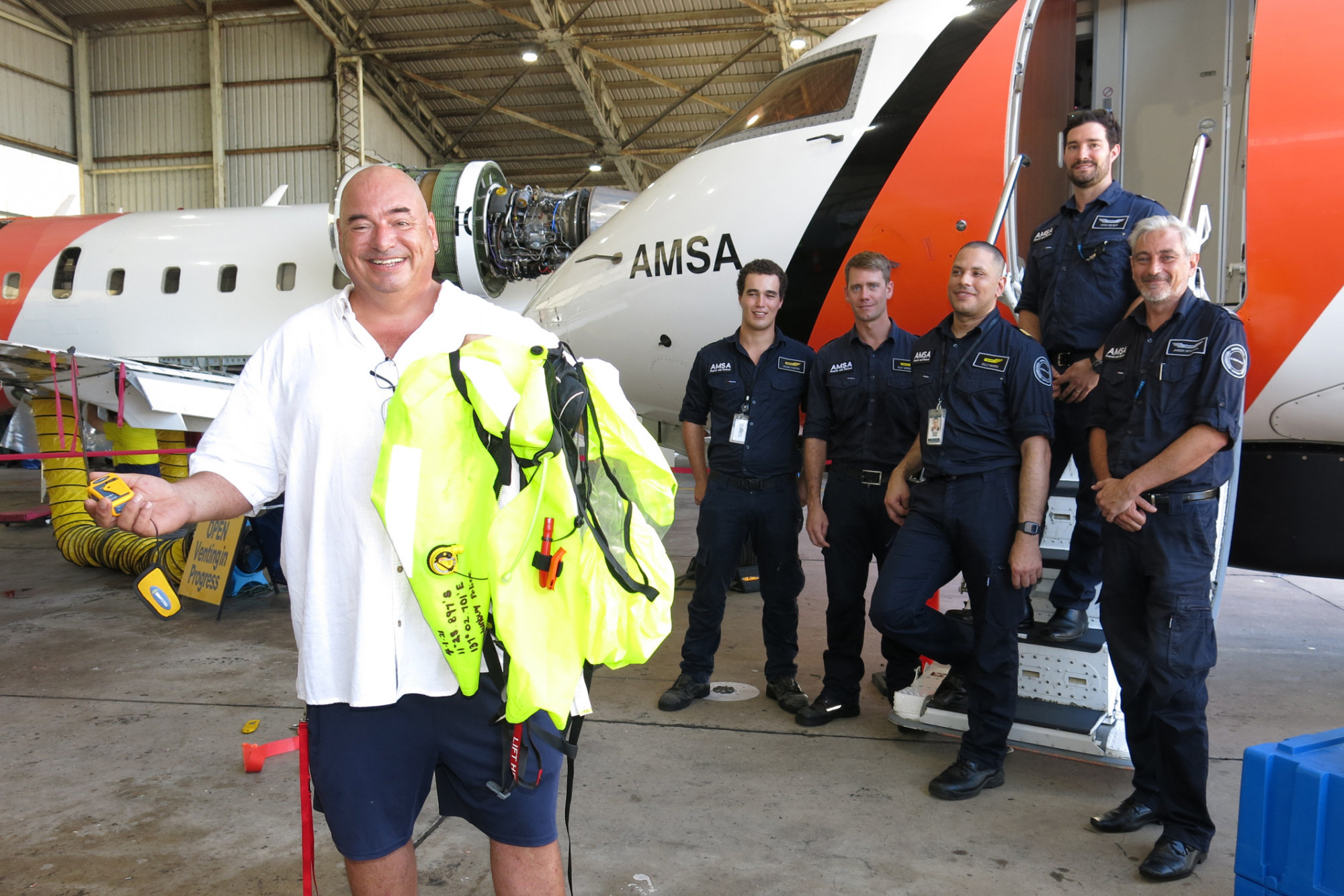 Sailor Nigel Fox (left) shows the Personal Locator Beacon and life jacket which saved his life, while meeting his air crew rescuers Jacob Porter, Ray Wedmaier, Mission Coordinator Olly Marin, Captain Kris Reiser and First Officer Jason Mitchell. PHOTO: Tanya Murphy