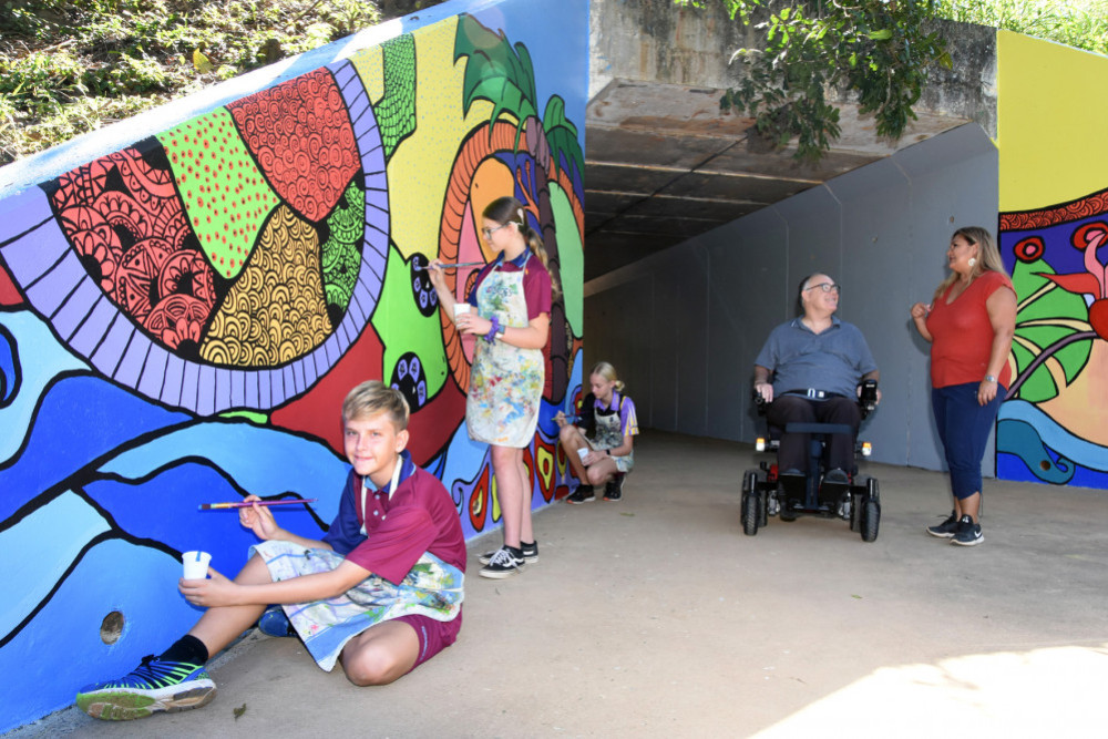 Bentley Park College Year 8 students (from left) James Threadingham, Ashlee Neiwand-Thomas and Hannah Tynan, with Division 2 Councillor Rob Pyne and artist Sharon Wedel at the newly painted Sinclair Miller Bridge underpass mural.