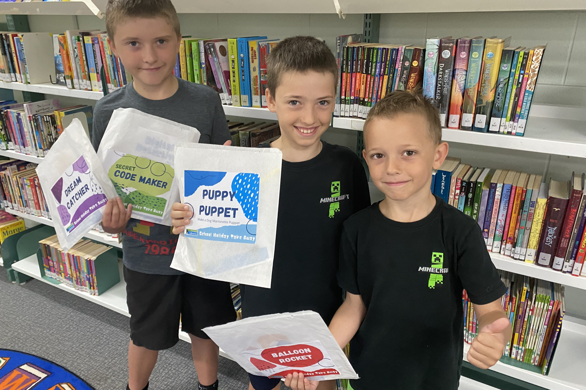 Minecraft fans Luc McBride, Tom McBride and Otis Kain with school holiday Take Away packs from Wongaling Beach Library