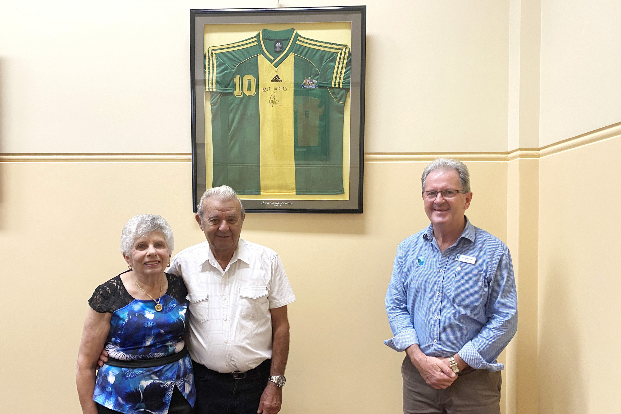 Mary and Mario Corica with Mayor Nolan in front of Steve’s signed Socceroo strip in the Mayor’s office.