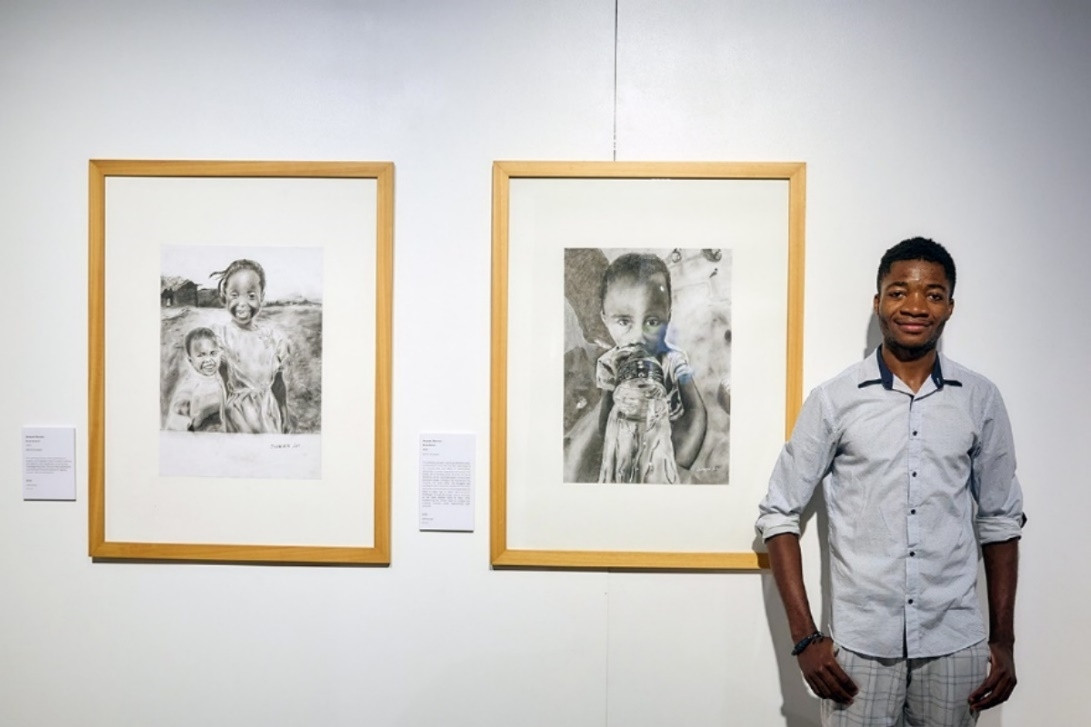 Young creative Jacques Baruani at the 2025 FLAME Visual exhibition launch, in front of his artworks ‘Back Home’. Picture: Romy Photography.