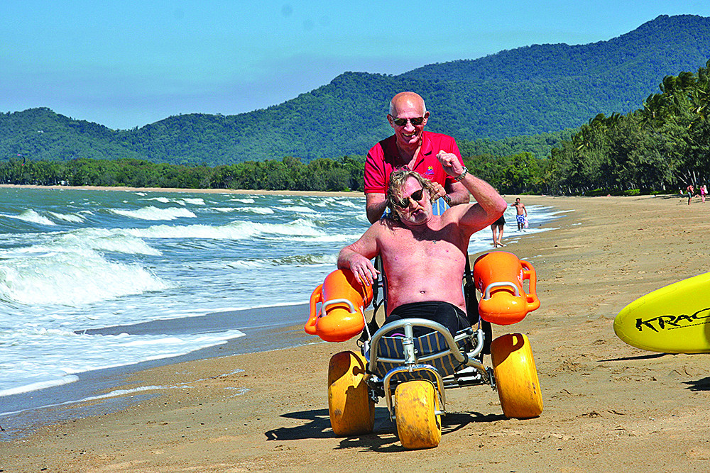 Mayor Bob Manning helps Chris Wighton with the float chair along the beach at Palm Cove.