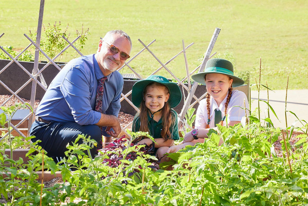 TAS White Rock Primary head Peter Gazzola with two primary school students in the vegetable patch. Picture: Trinity Anglican School