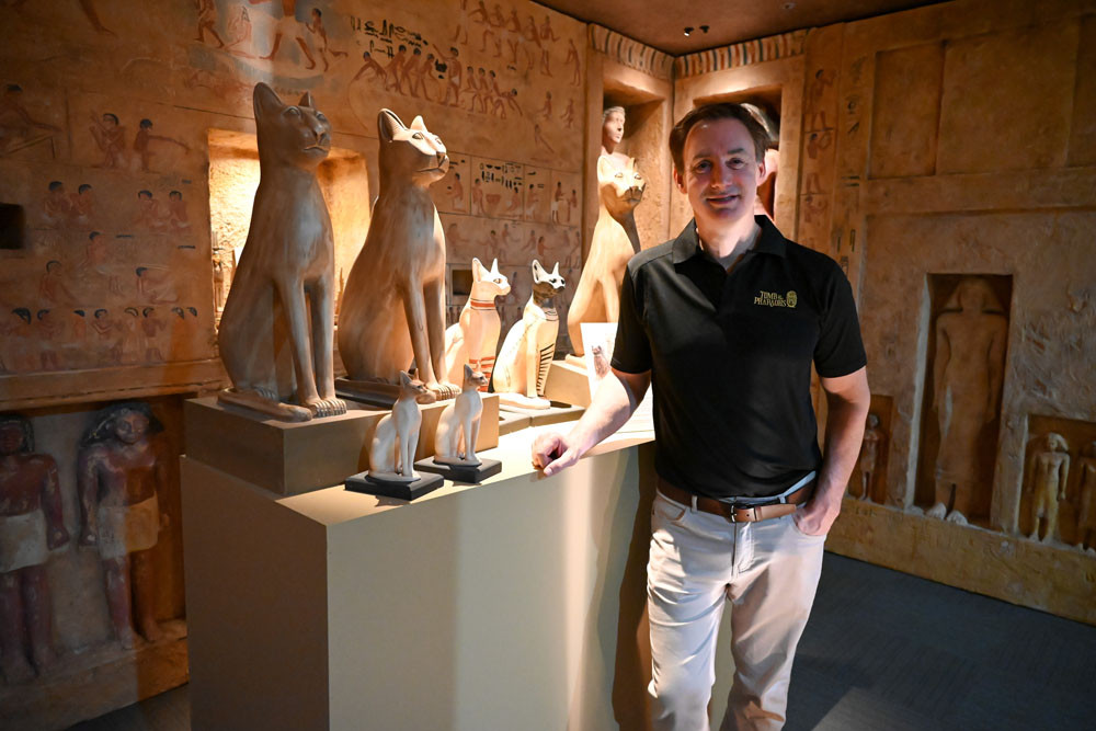 Daniel Leipnik, CEO and founder of Tomb of the Pharaohs, stands beside a display of ancient Egyptian cat statues, symbolising the revered goddess Bastet. Picture: Lizzie Vigar