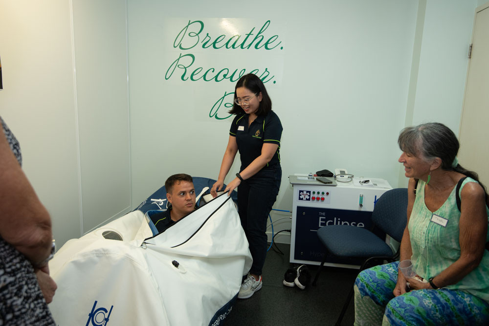 Nicolas Olguin (in the chamber) tests out the HBOT demonstration with physiotherapist Pia Madarang at Wellness Embodied’s CBD clinic.