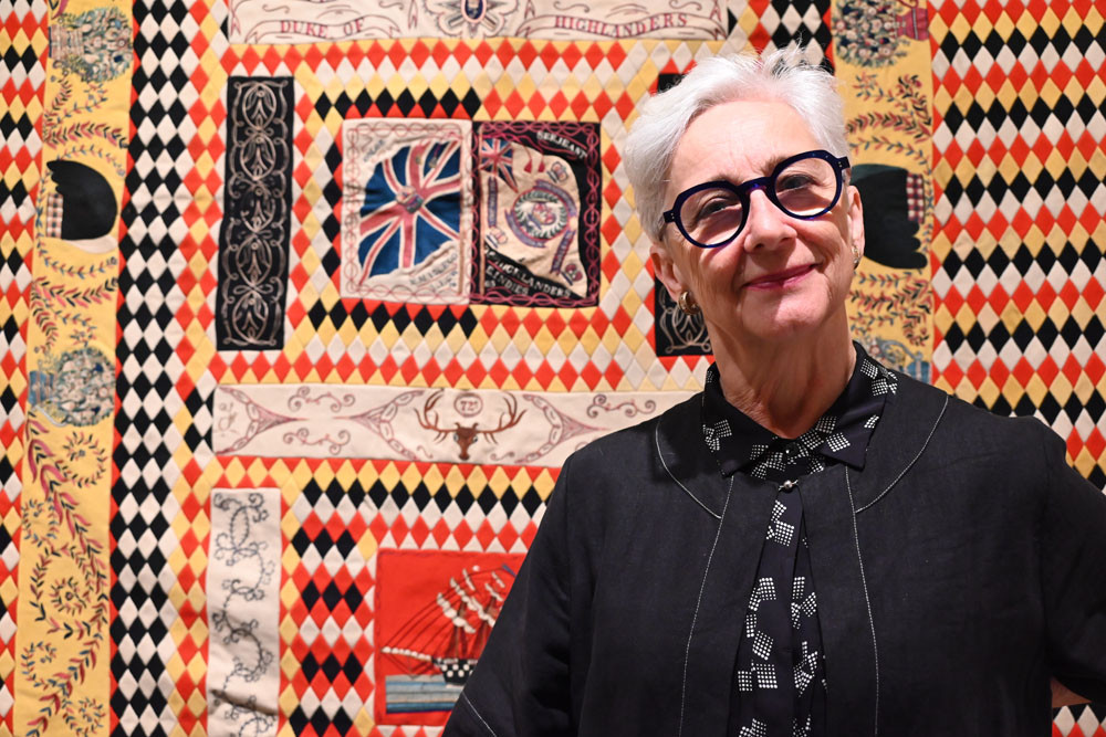 Cairns Art Gallery senior curator Ingrid Hoffman with a mid-Victorian regimental bed rug made by Sgt. Malcom Macleod in India before 1868. Picture: Isabella Guzman Gonzalez