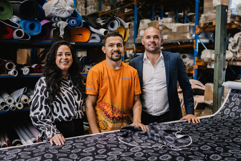 Cairns visual artist Jedess Hudson (left), upholsterer Brendan Ward-Anning and YINDI founder Ramon Close with the pattern for the Officeworks collection. Picture: Supplied