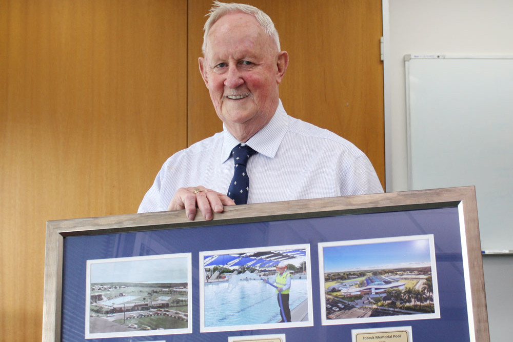 Cr Max O’Halloran with one of his parting gifts – a framed photograph commemorating the Tobruk Memorial Pool redevelopment. Picture: Cairns Regional Council