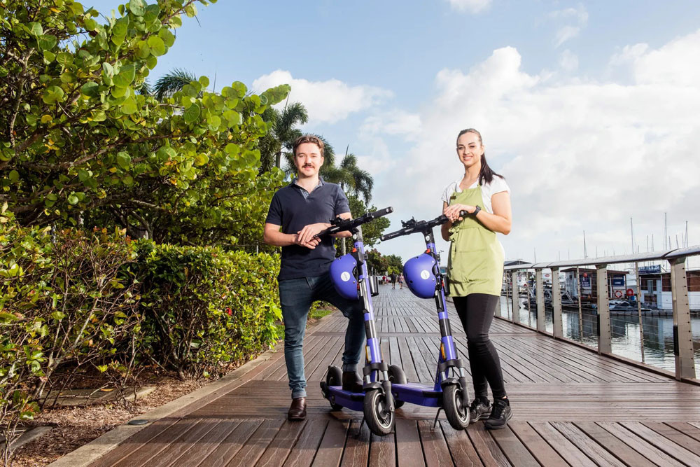 Beam e-scooter users on the Cairns waterfront.