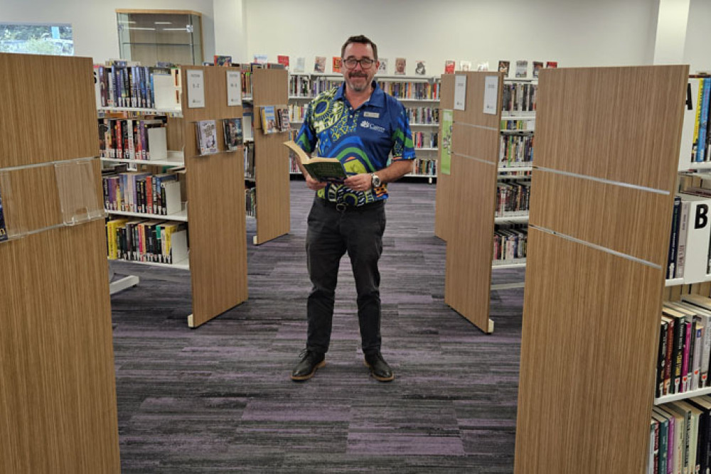 Manunda librarian Dan Guest checks out one of the 6200 books at the new library at Raintrees shopping centre. Picture: Nick Dalton
