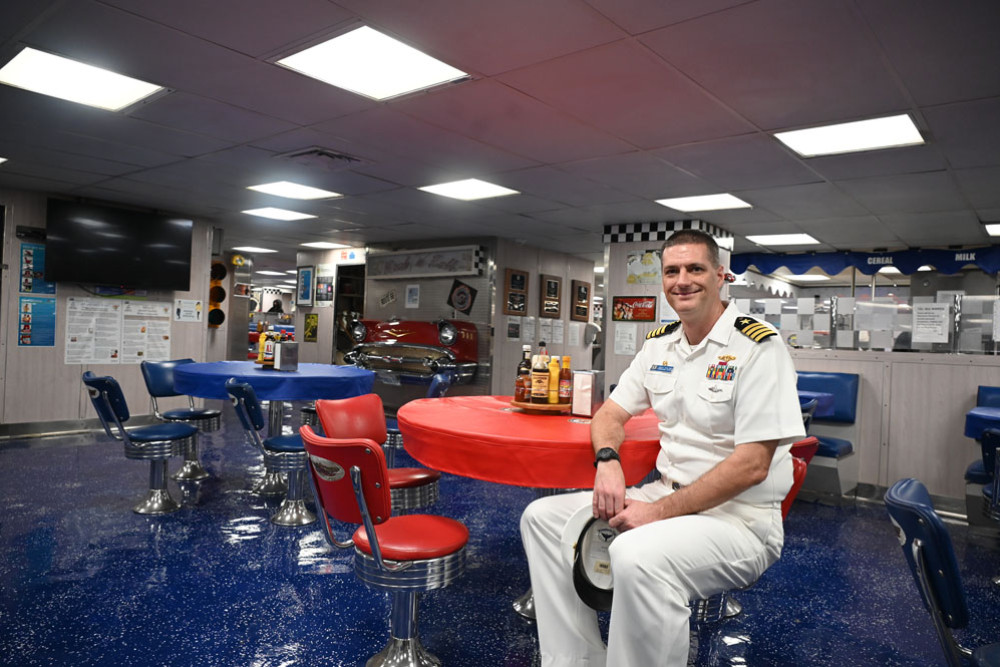 Captain Brent Spillner in the 50s diner-themed dining room inside the (inset picture) USS Emory S. Land. Pictures: Maddy Gavin