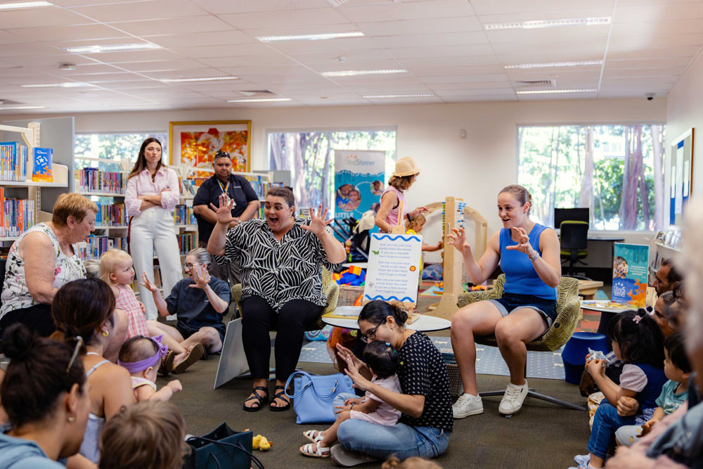Cairns Libraries First 5 Forever project officer Jemima Eveans (left) and tennis champion Ash Barty read to children and their grandparents at Cairns City Library. Picture: Nic Morley
