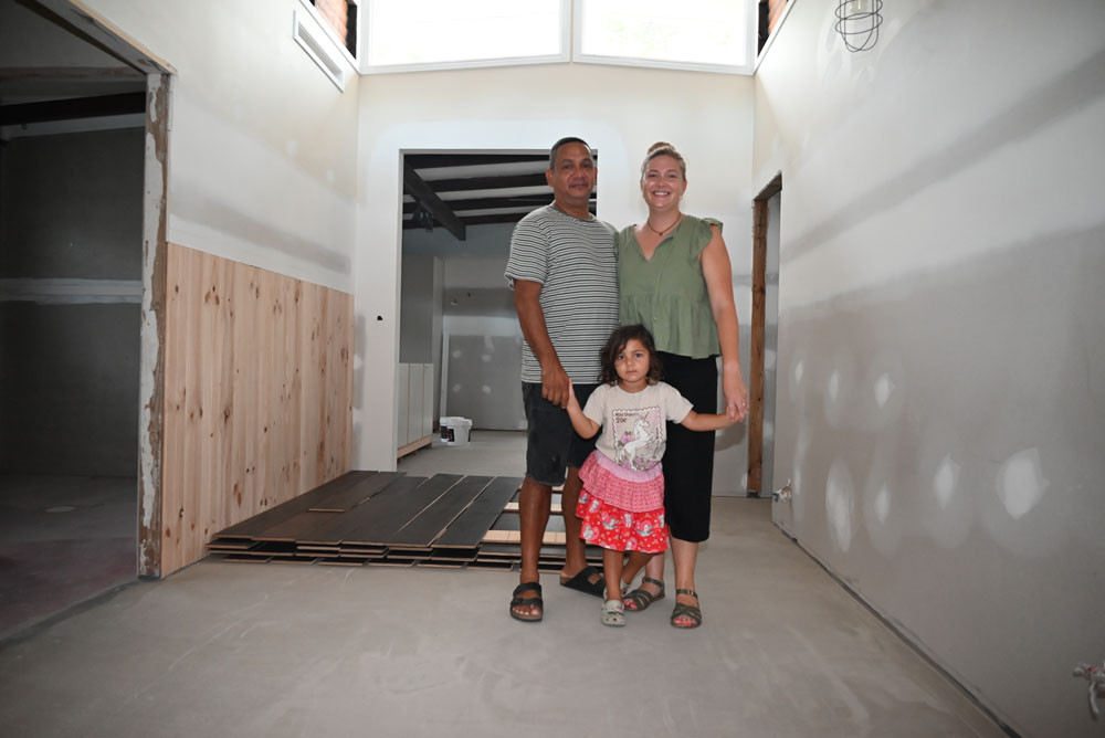 Jason Fagan (left), Kirby Murtha and their daughter Zali from Machans Beach inside their home on Christensen St which is still being renovated after the floods.