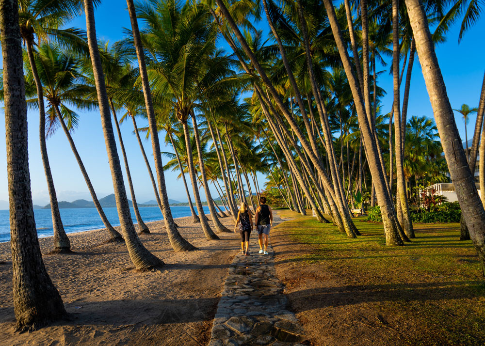 A couple take a morning stroll along the picturesque Palm Cove beachfront. Picture: Tourism Tropical North Queensland