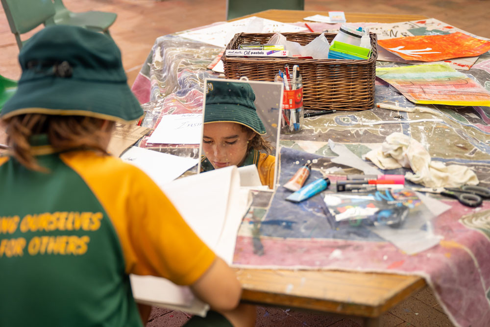 Noah Shaw using a mirror to work on his self-portrait, Simple.