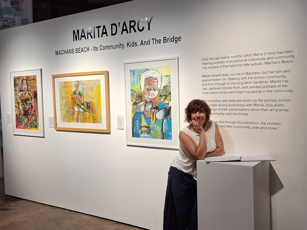 Artist Marita D’Arcy at her exhibition with Mary Saveka’s portrait, an acrylic on paper she entitled “Because” behind her. Pictures: Emily Barker of FNQ Roar Media & Photography