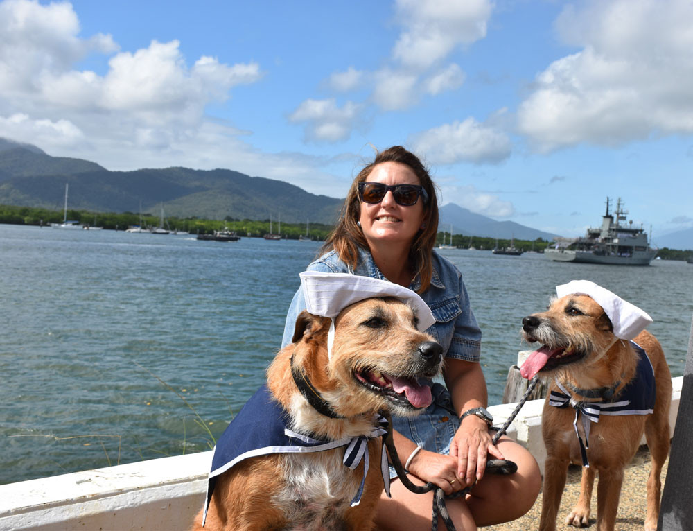Beck Goodall with pups Enzo and Jobe with HMAS Melville sailing by in the background. Pictures: Isabella Guzman Gonzalez