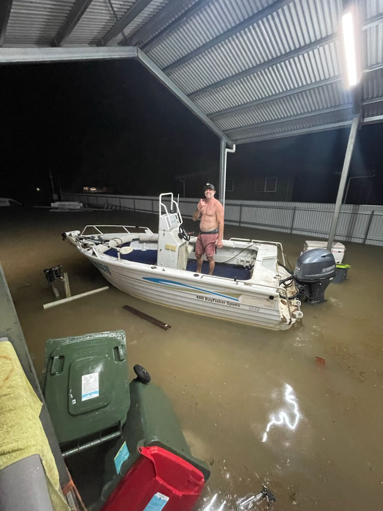 Brent Churton on a boat in his flooded garage at Cardwell. His family is now living with friends. Picture: Supplied. Inset: Empty shelves at Coles supermarket at Earlville Shopping Town this week. Picture: Isabella Guzman Gonzalez