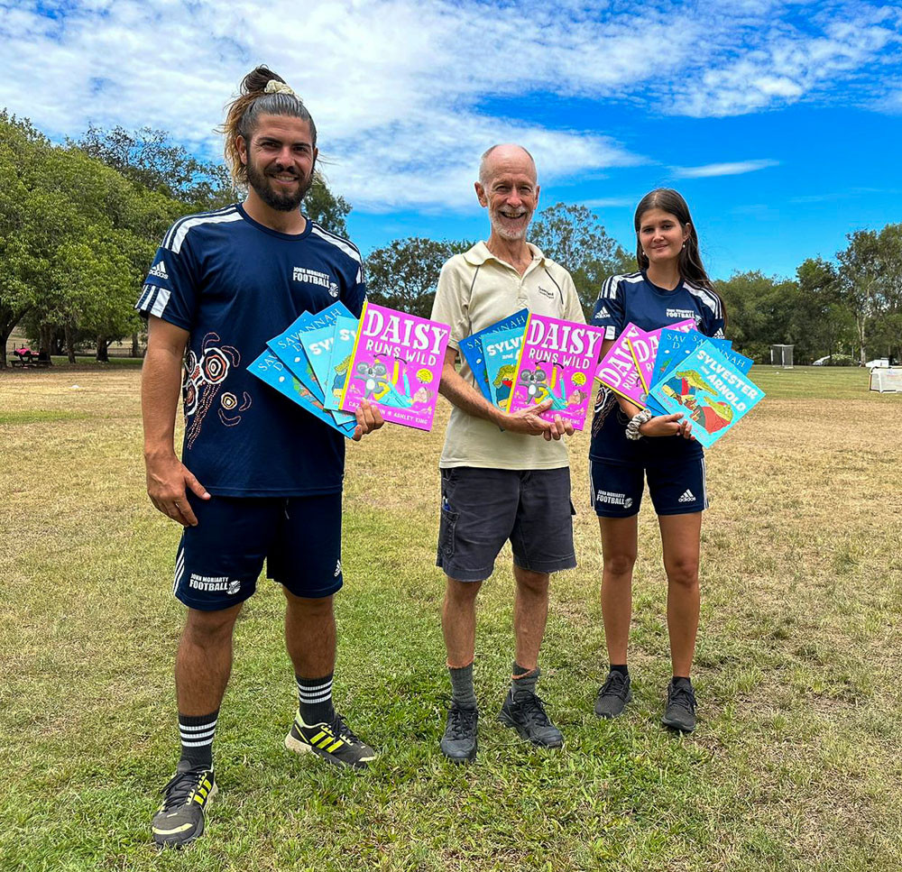 Cristian Couto, Bill White and Tia Hewitt with some of the books donated to Mareeba State Primary School