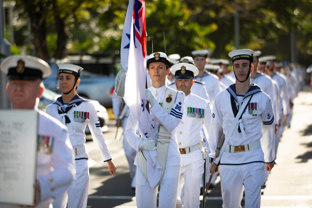 Royal Australian Navy sailor Petty Officer Physical Training Instructor Holly Lloyd, displays the Royal Australian Navy White Ensign in front of the city of Cairns during a Freedom of Entry March. Image by ABIS Susan Mossop