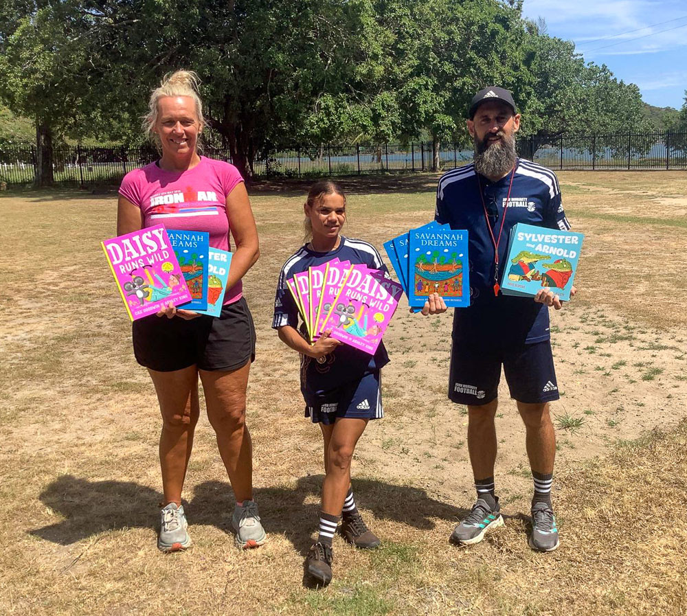 Emma Cook, Edyara Tabuai and Steven Stefanopoulos with some of the books donated to Yarrabah State School