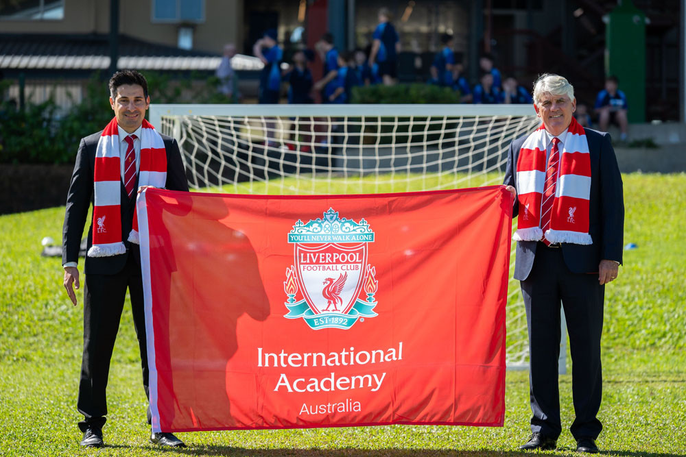Liverpool FC head coach Kevin Grima presented a Liverpool FC flag to Good Counsel College Principal Paul Melloy. CREDIT: Mark Law